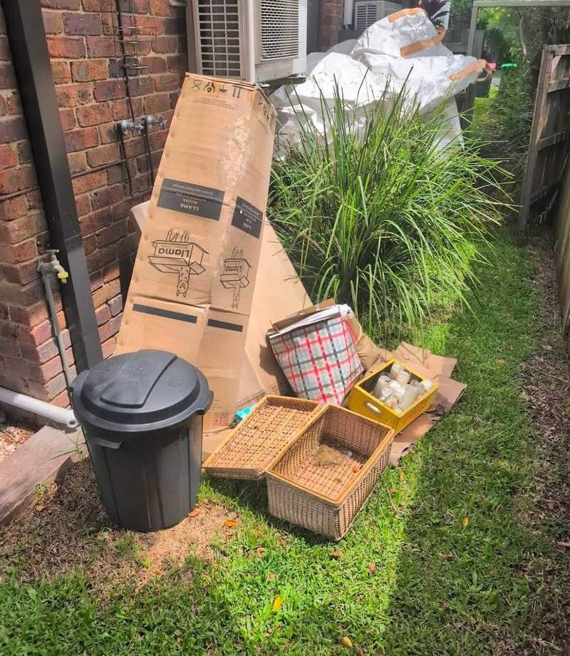 Boxes, bins and baskets stacked down the side of a house before removal