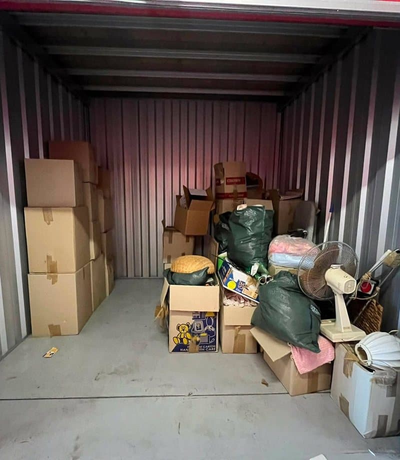 Storage unit packed with boxes, bags and household goods before clear-out